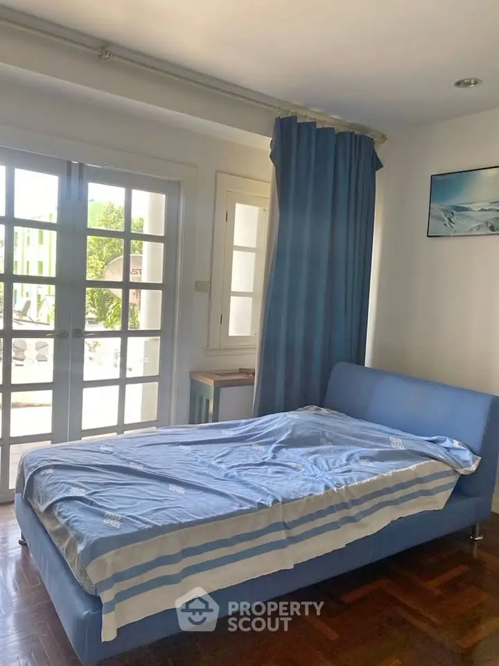 Cozy bedroom with blue decor and large windows for natural light.