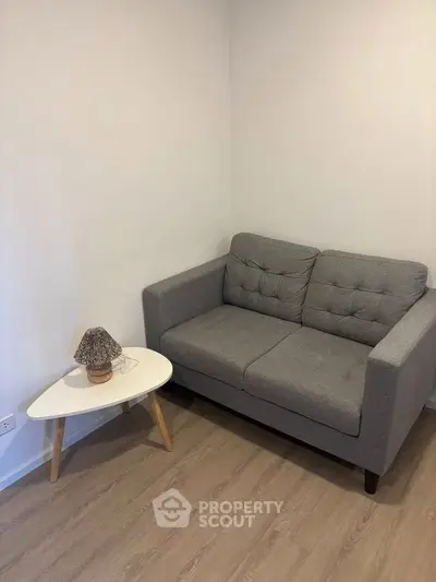 Cozy living room corner with a stylish gray sofa and modern side table, perfect for relaxation.