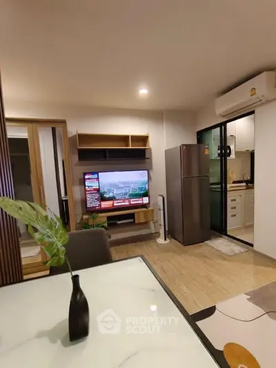 Modern living room with open kitchen, featuring sleek appliances and stylish decor.