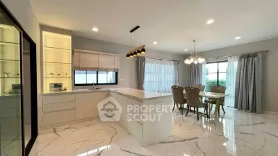 Luxurious open-layout kitchen and dining area with modern lighting and marble flooring.