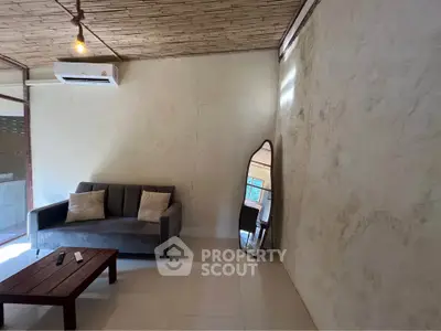 Cozy living room with modern sofa, stylish mirror, and air conditioning in a rustic setting.