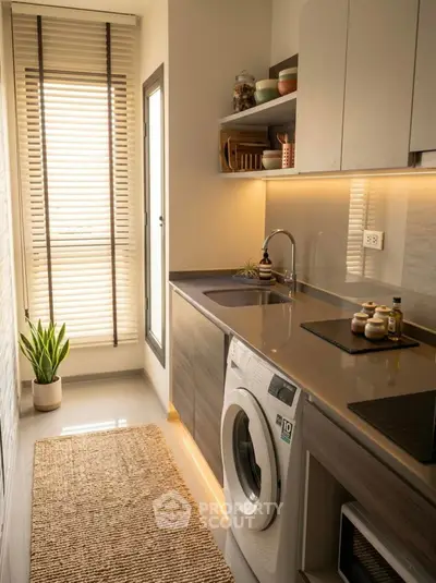 Modern kitchen with washing machine and sleek cabinetry, featuring natural light and stylish decor.