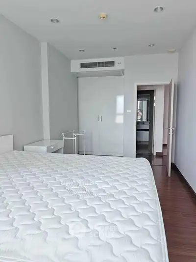 Spacious bedroom with modern design and ample natural light, featuring a large bed and built-in wardrobe.