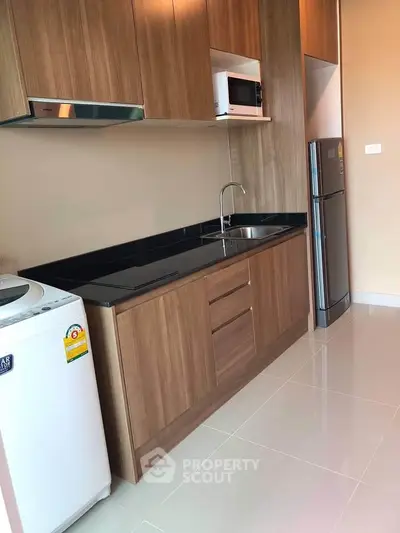 Modern kitchen with wooden cabinets, sleek appliances, and washing machine.