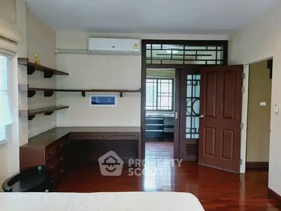 Spacious bedroom with wooden floors and built-in shelves, featuring a modern design.