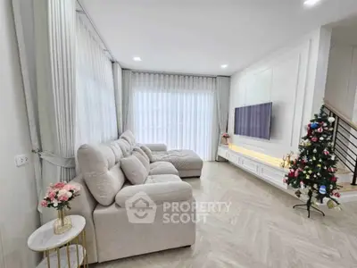 Elegant living room with plush sofa, modern TV setup, and festive Christmas tree, perfect for cozy gatherings.
