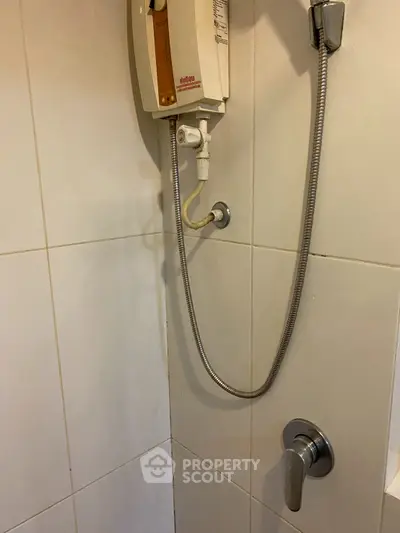 Compact bathroom shower area with water heater and modern fixtures.