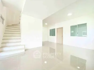 Spacious modern living room with glossy tiled floors and staircase