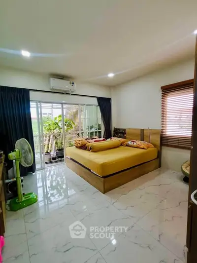 Spacious bedroom with large windows and balcony access, featuring modern decor and ample natural light.