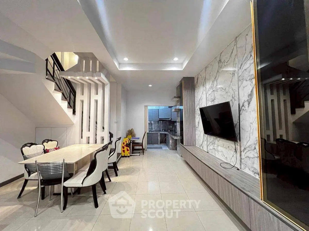 Modern open-plan living and dining area with stylish decor and wall-mounted TV.