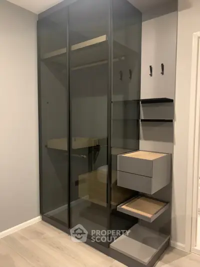 Modern storage unit with sleek glass doors and wooden shelves in a stylish interior.