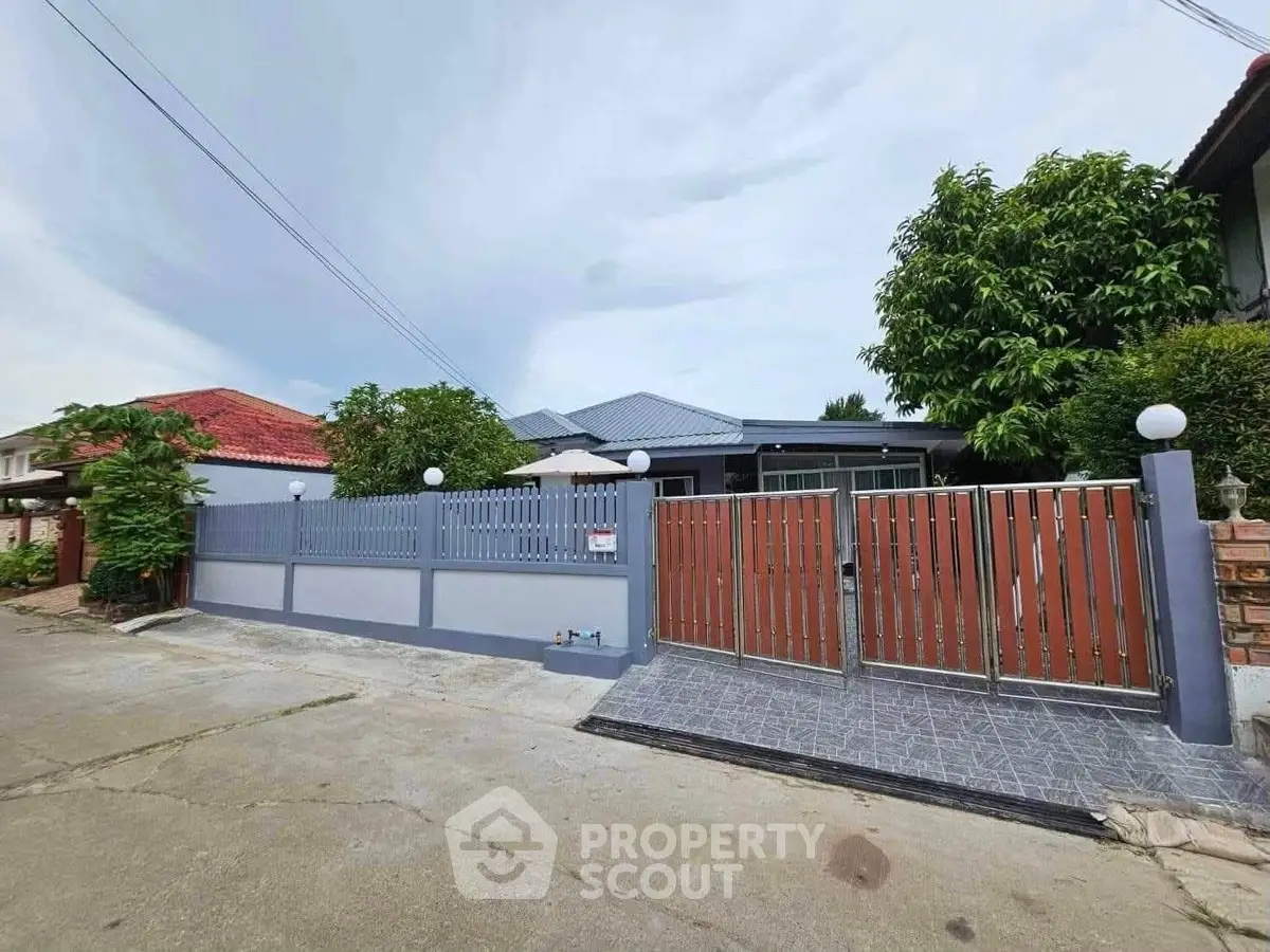 Charming single-story home with modern fence and lush greenery in a serene neighborhood.