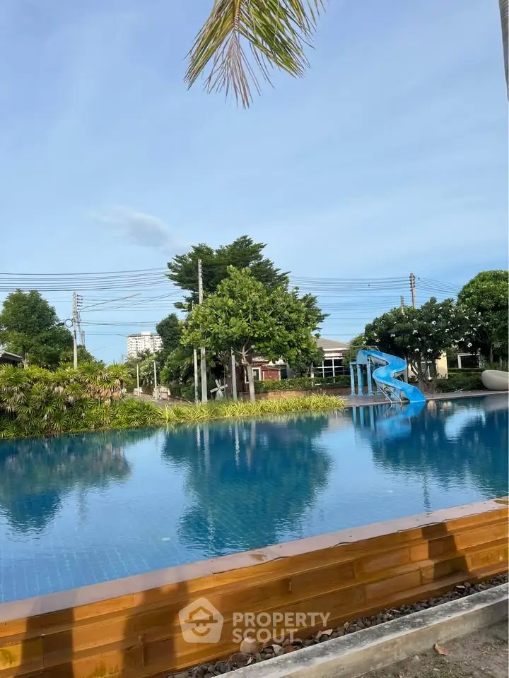 Stunning outdoor pool with lush greenery and a fun slide, perfect for relaxation and recreation.