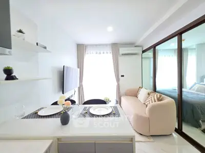 Modern open-plan living room with cozy sofa and dining area, featuring sleek decor and natural light.