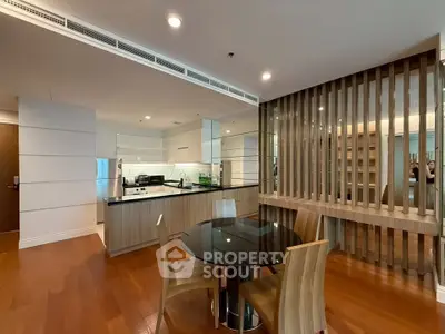 Modern open-plan kitchen and dining area with sleek wooden flooring and stylish furniture.