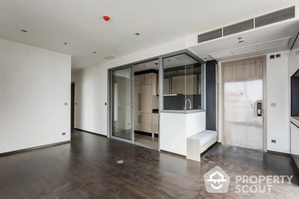 Spacious modern apartment with dark hardwood floors, large windows, and a sleek kitchen with integrated appliances, perfect for urban living.