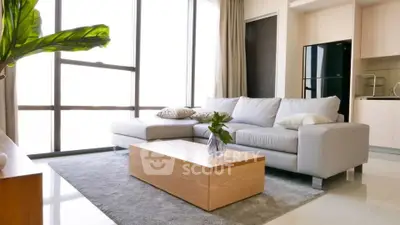 Modern living room with large windows, stylish sofa, and sleek kitchen area.