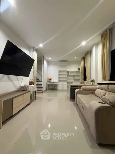 Spacious modern living room with sleek design and large TV, perfect for relaxation and entertainment.