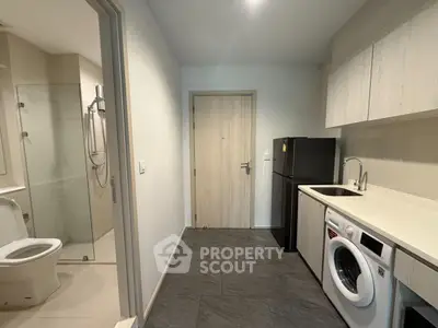 Modern apartment with compact kitchen and bathroom, featuring washing machine and sleek design.