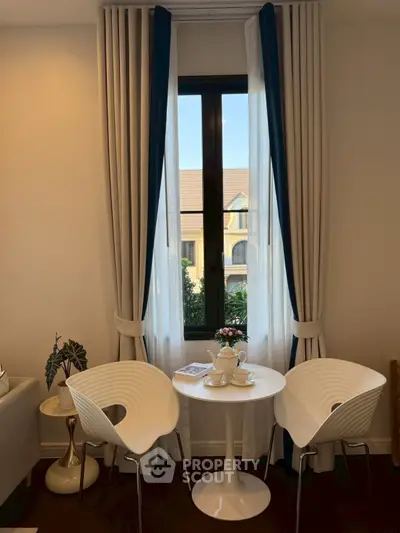 Charming interior with elegant window view and cozy seating area, perfect for relaxation and enjoying natural light.