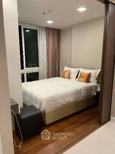 Cozy modern bedroom with wooden flooring and large window view.