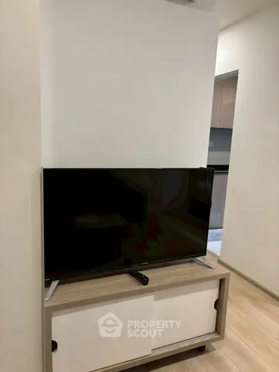 Modern living room with sleek TV stand and flat-screen TV, showcasing minimalist design.