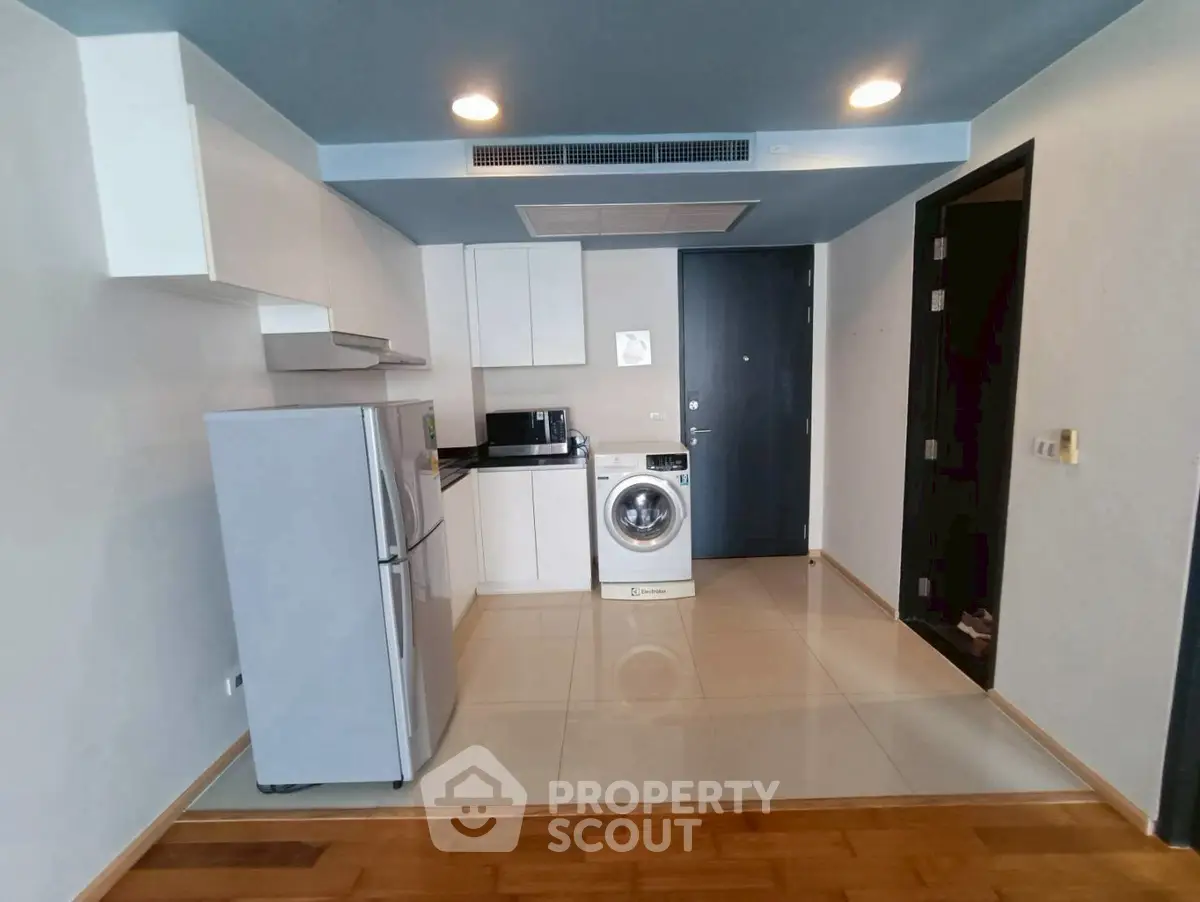 Modern kitchen with sleek appliances and washing machine in compact layout