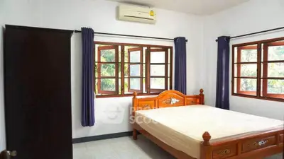 Spacious bedroom with wooden bed frame and large windows for natural light.