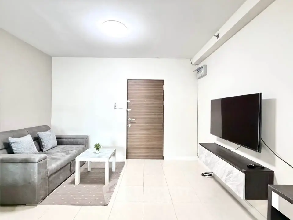 Modern living room with sleek furniture and wall-mounted TV, perfect for relaxation and entertainment.