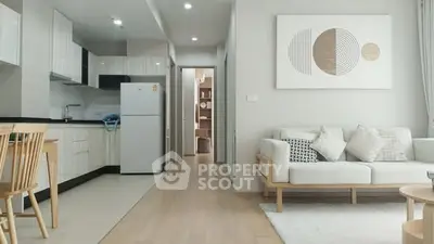 Modern open-layout living room with kitchen, featuring stylish decor and natural light.