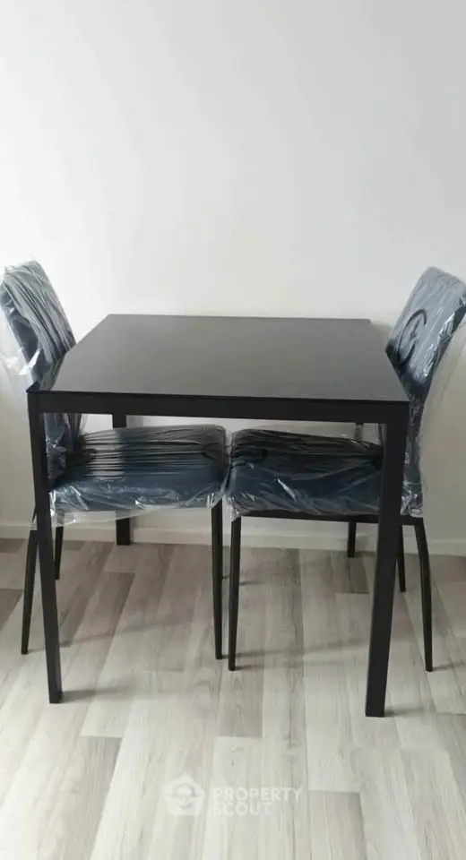 Modern dining set with sleek black table and chairs on stylish wooden flooring.