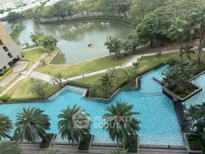 Luxurious residential complex with stunning pool and lush greenery overlooking a serene waterway.