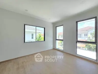 Bright empty room with large windows and wooden flooring, ideal for customization.