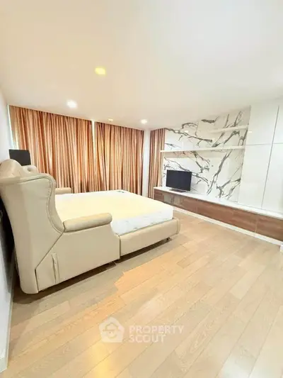 Spacious bedroom with elegant marble accent wall and cozy lighting