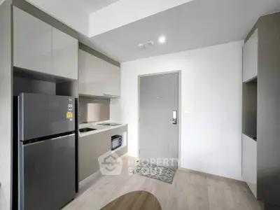 Modern kitchen with sleek cabinetry and stainless steel appliances in a compact apartment.