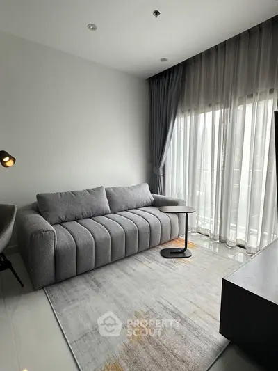 Modern living room with stylish gray sofa and floor-to-ceiling windows for natural light.