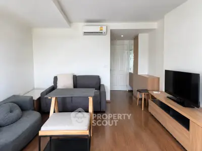 Modern living room with sleek furniture and wooden flooring, featuring a cozy sofa and flat-screen TV.