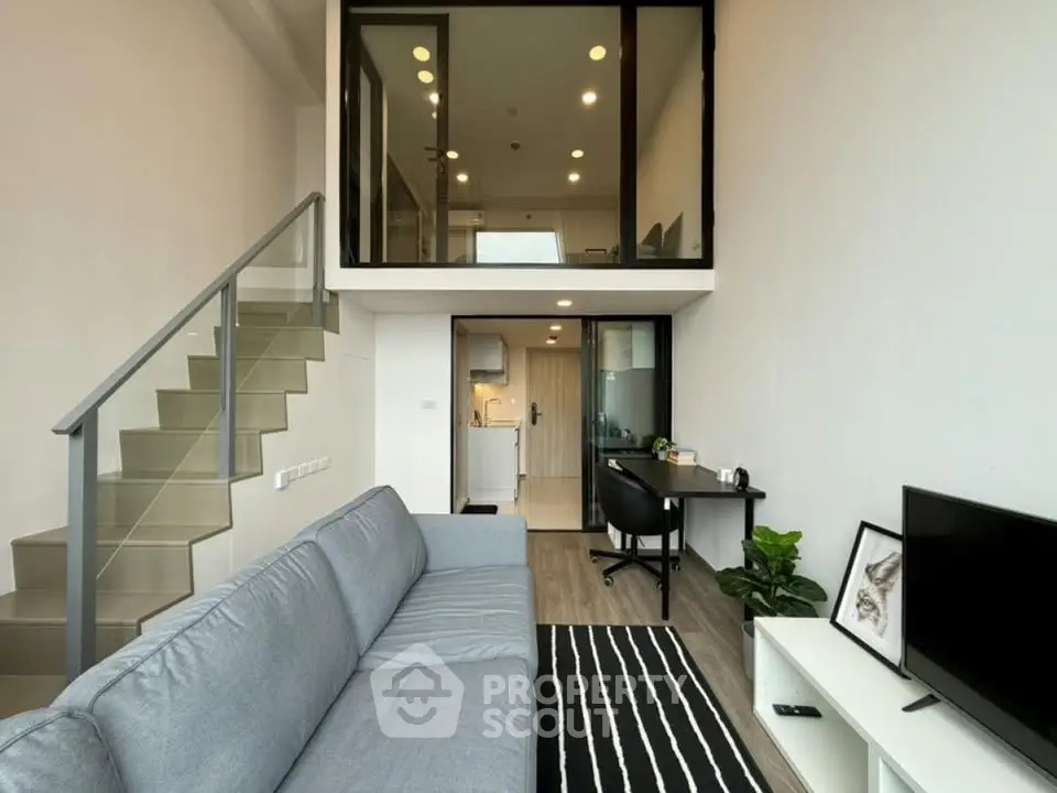 Modern loft apartment with stylish living room and mezzanine level, featuring sleek staircase and contemporary decor.