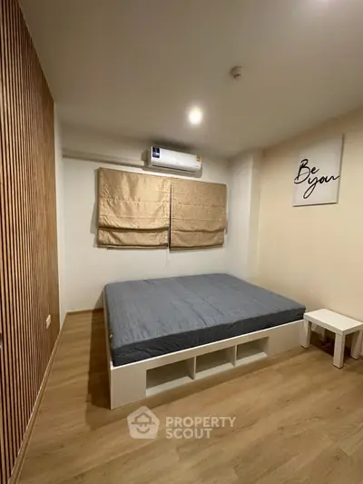 Modern minimalist bedroom with wooden flooring and stylish wall art
