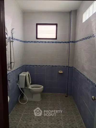 Modern bathroom with tiled walls and floor, featuring a shower and toilet.