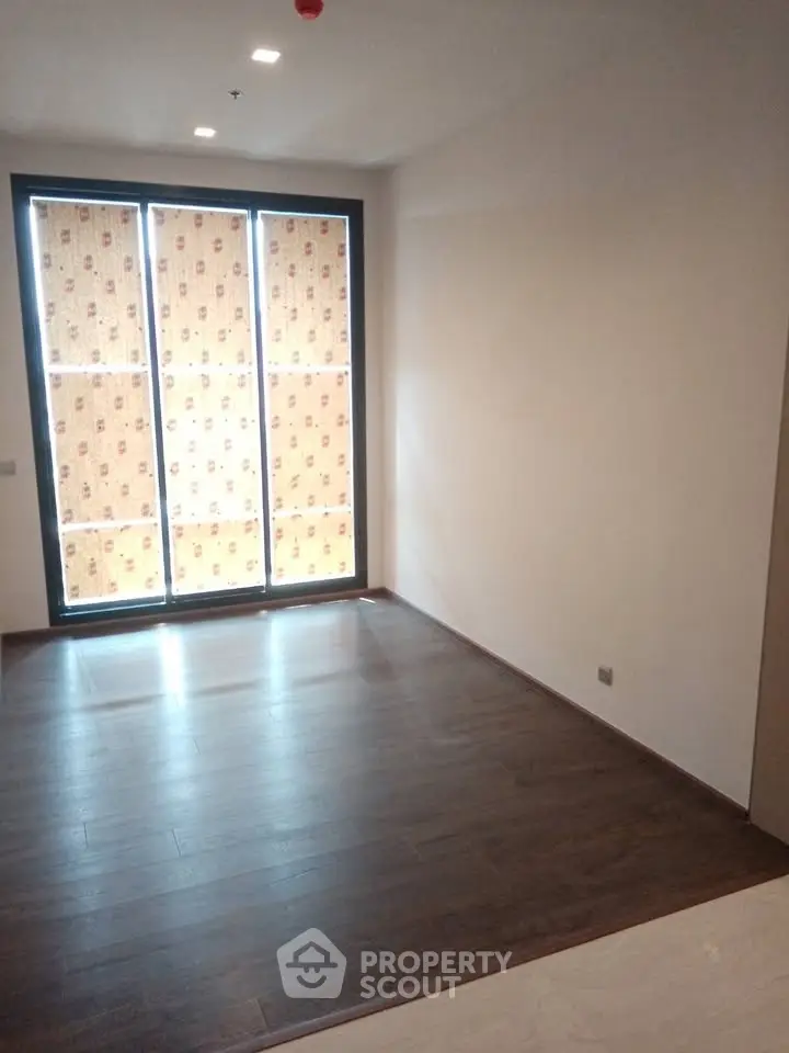 Spacious empty room with large windows and wooden flooring, perfect for customization.