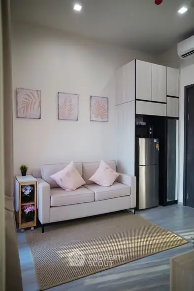 Modern living room with stylish decor and compact kitchen area, featuring a cozy sofa and sleek appliances.
