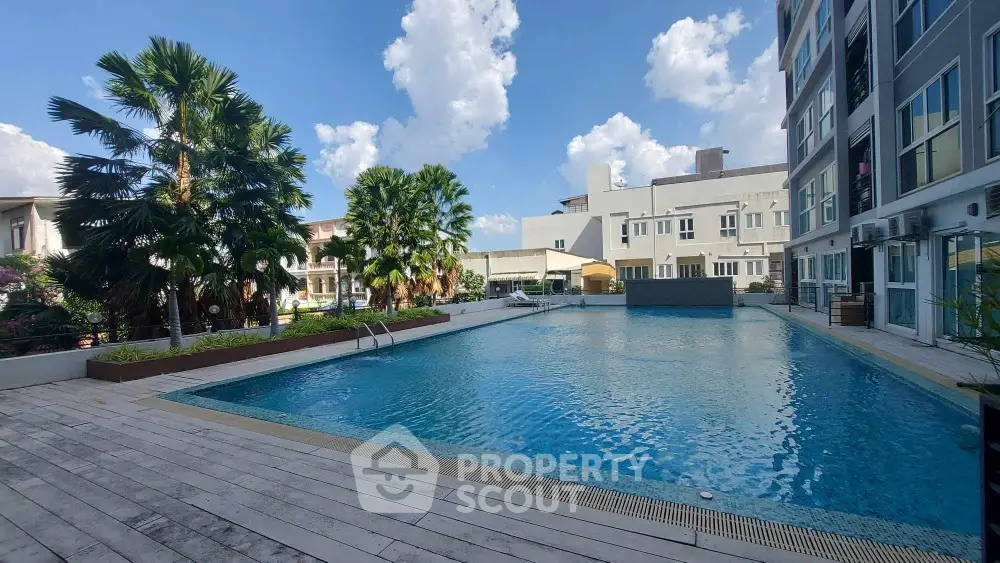 Luxurious residential pool area with modern building and lush greenery