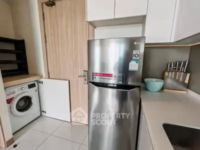 Modern kitchen with stainless steel fridge and washing machine in compact layout.