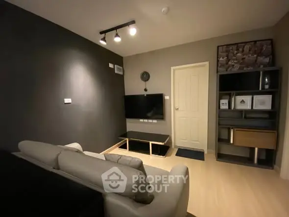 Modern living room with sleek furniture and wall-mounted TV in cozy apartment.