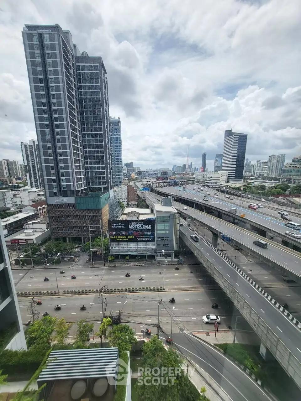 Stunning cityscape view from high-rise building overlooking busy highway and urban skyline.
