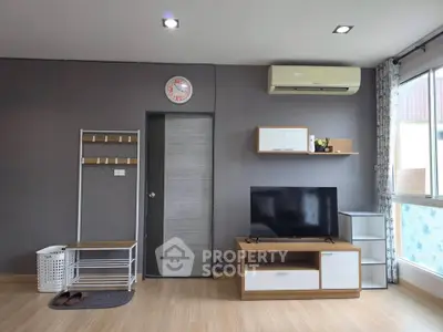 Modern living room with sleek furniture and air conditioning, featuring a wall-mounted TV and stylish decor.