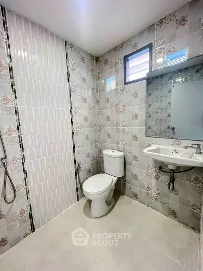 Modern bathroom with floral tiles, sleek fixtures, and natural light.