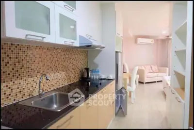 Modern kitchen with mosaic backsplash and open layout leading to living area