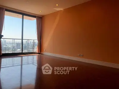 Spacious living room with large windows and balcony offering stunning city views.